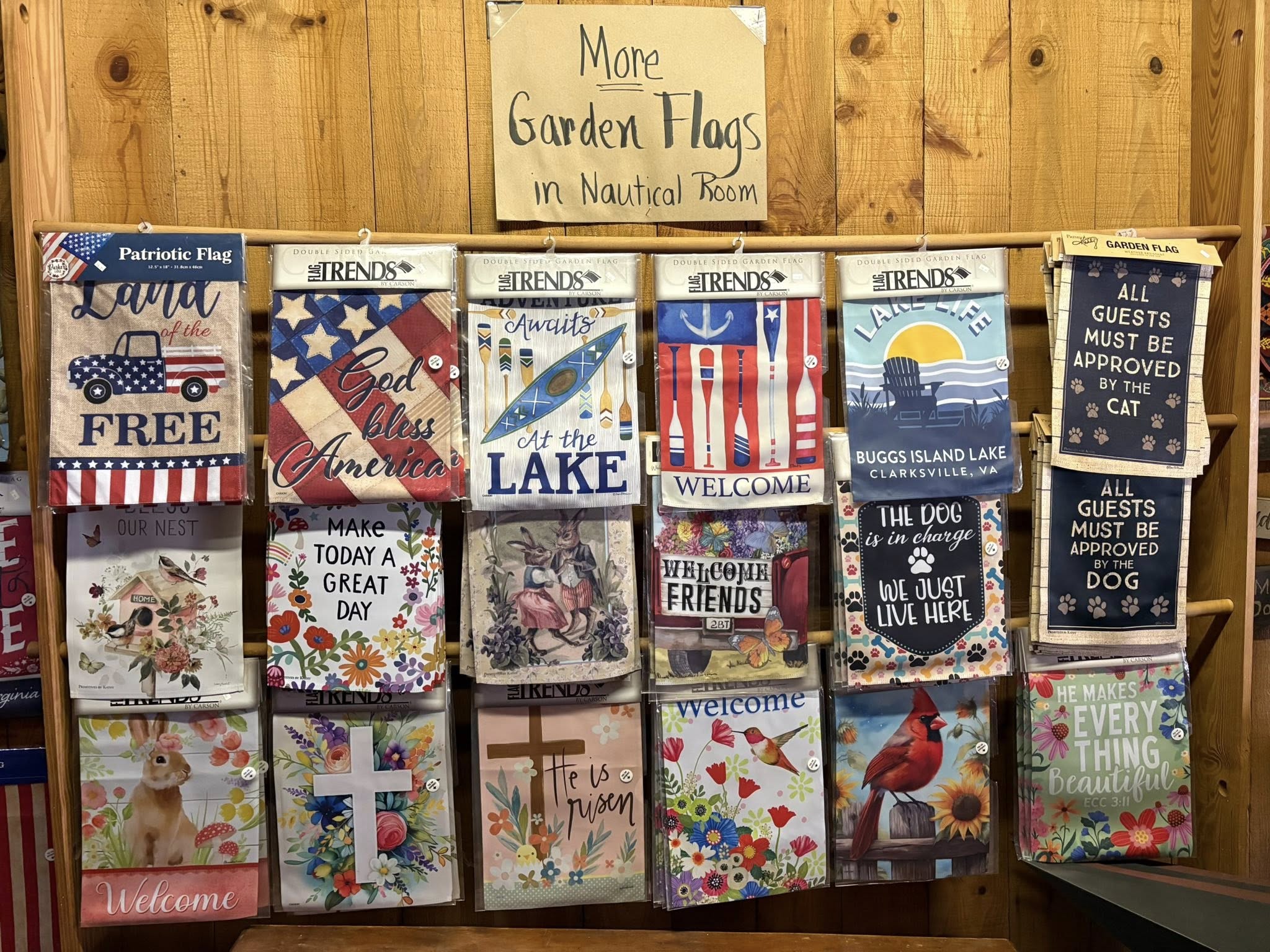 Display rack of colorful garden flags including patriotic, lake life, seasonal, and inspirational designs